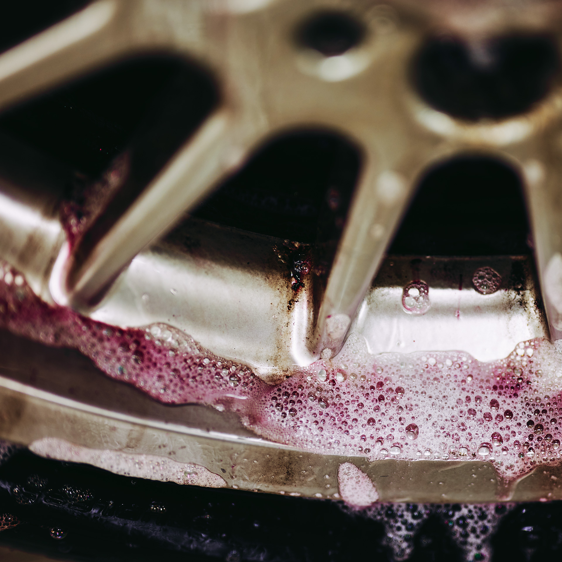 Rengaspyörän pesu vaahtoavalla Korrek Pro Irox punaisen värisen pesuaineella, kuplia ja vaahtoa näkyy metallirenkaassa.